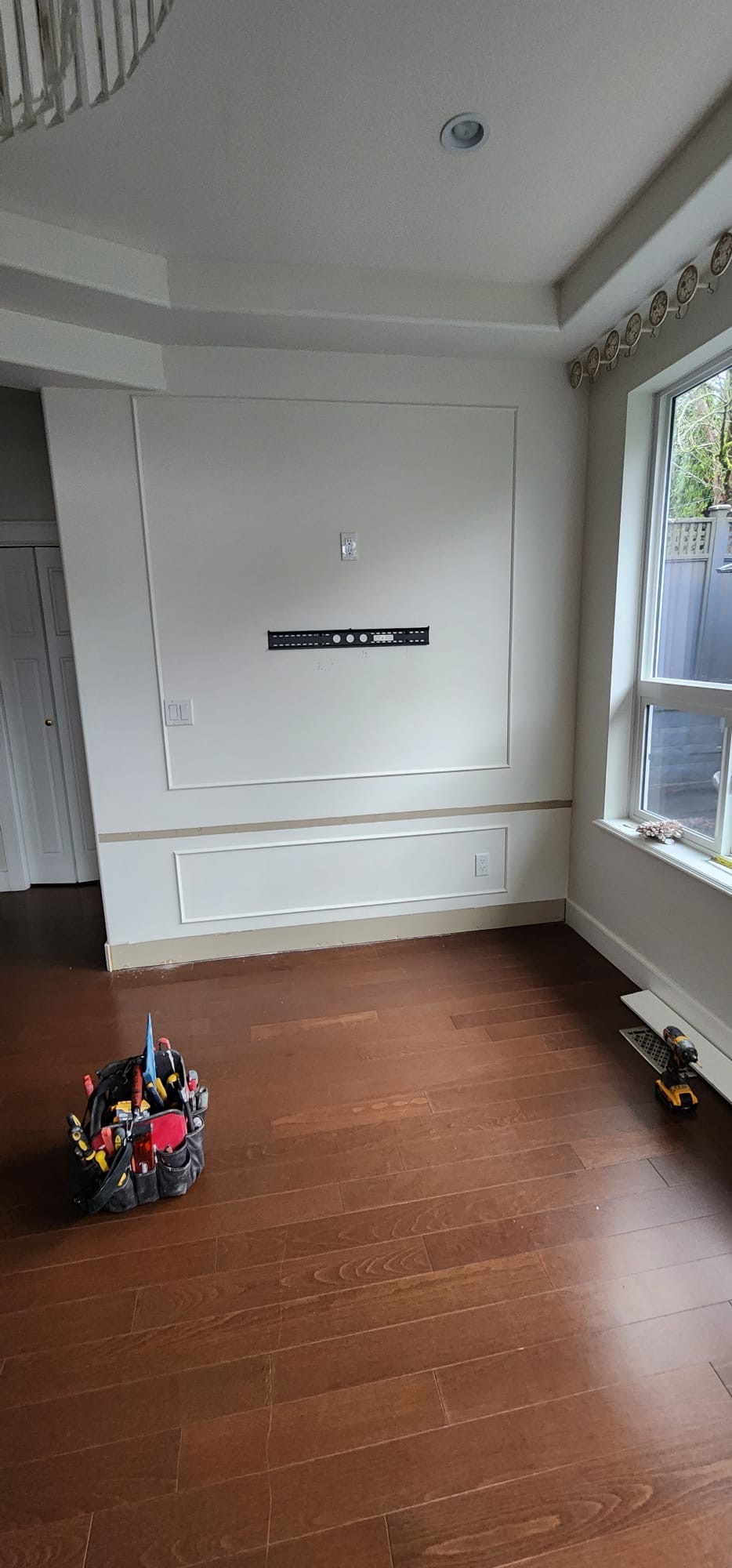 Feature wall before — bare wall with TV mount and trim