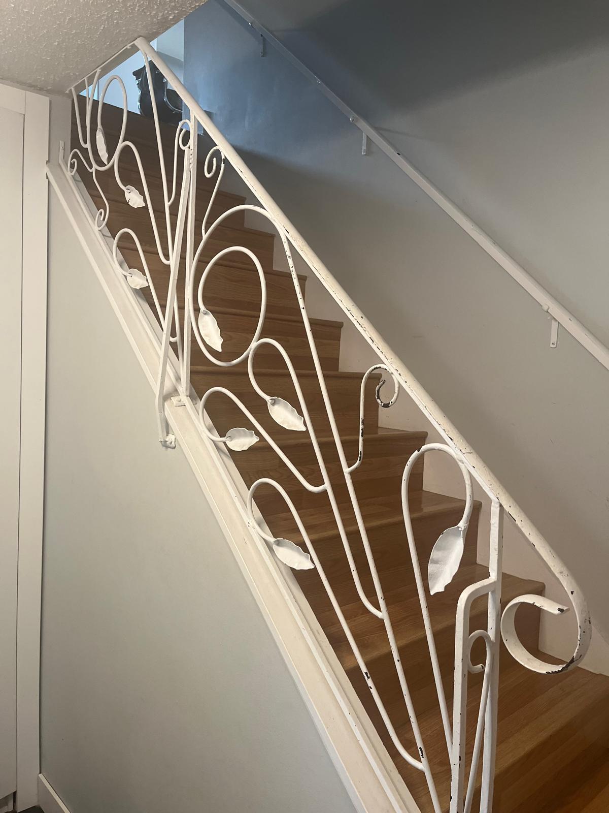 Stairwell before glass railing installation — old ornate wrought-iron railing