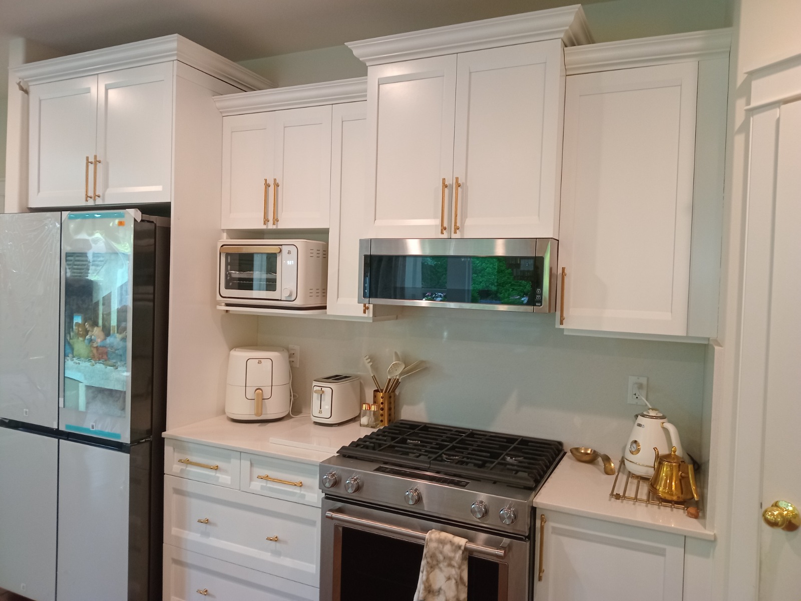 Kitchen after renovation — white shaker cabinets and gold hardware