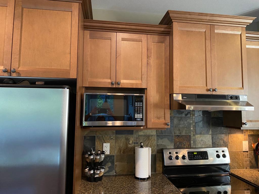 Kitchen before renovation — dark wood cabinetry with stainless microwave